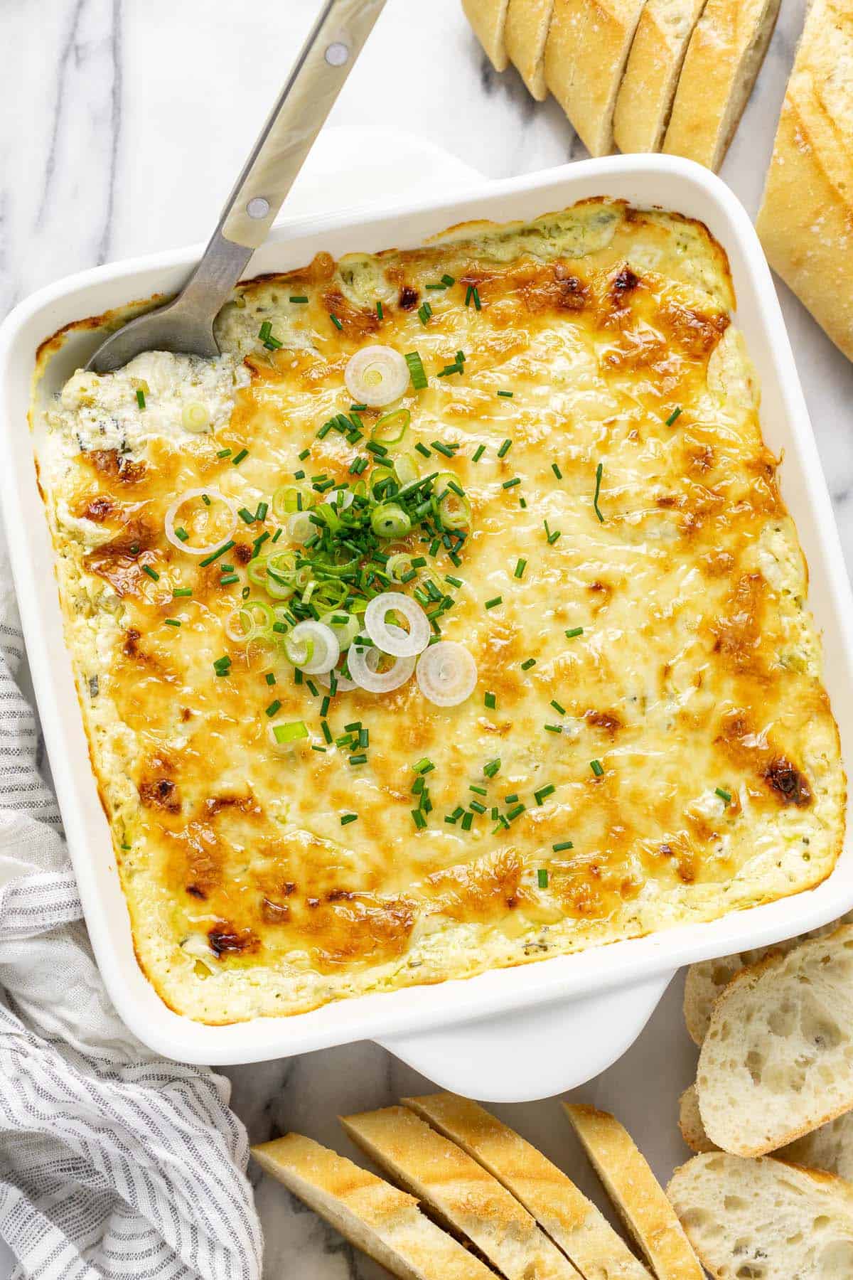 Baking dish filled with warm pepperoncini dip garnished with green onions and chives.