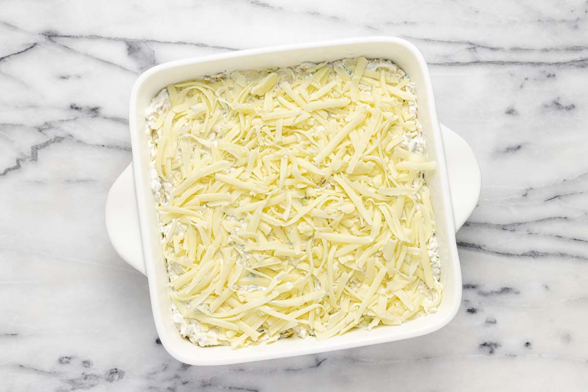 Baking dish filled with pepperoncini dip topped with cheese.