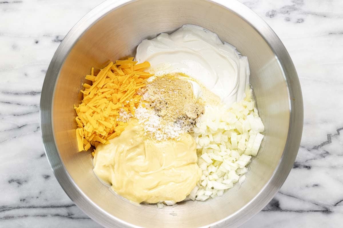 Large bowl filled with cheesy hashbrown sauce ingredients. 