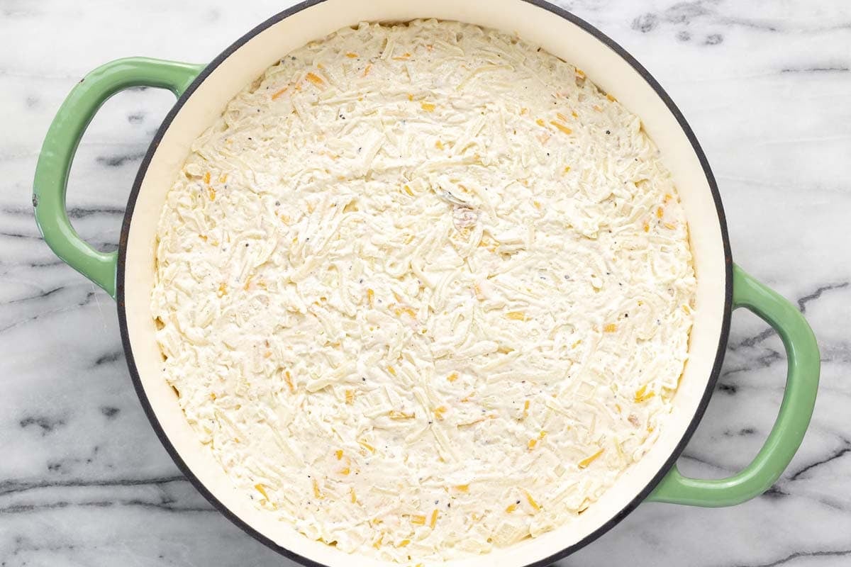 Cheesy hashbrown casserole spread in a large pan. 