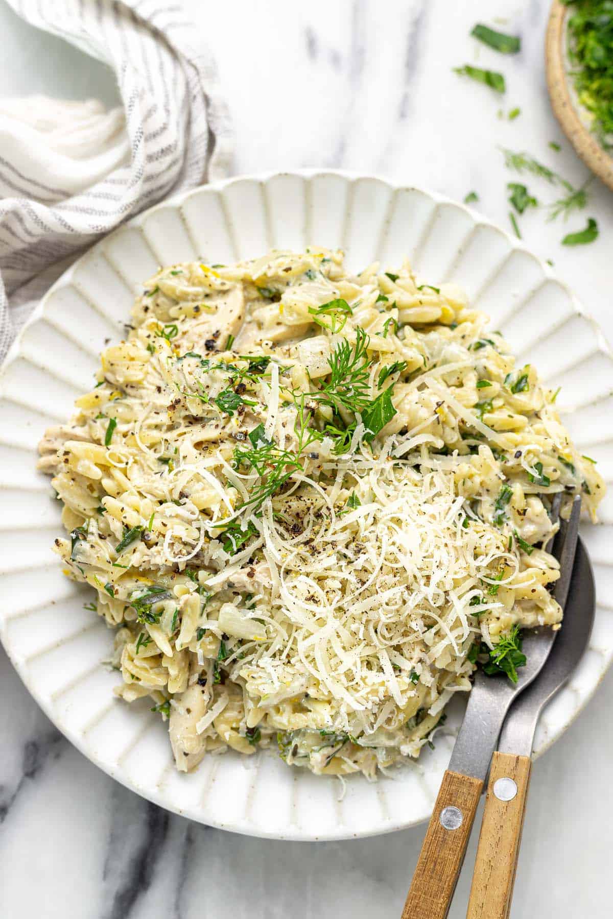 Plate of lemon chicken orzo garnished with fresh dill and parsley. 