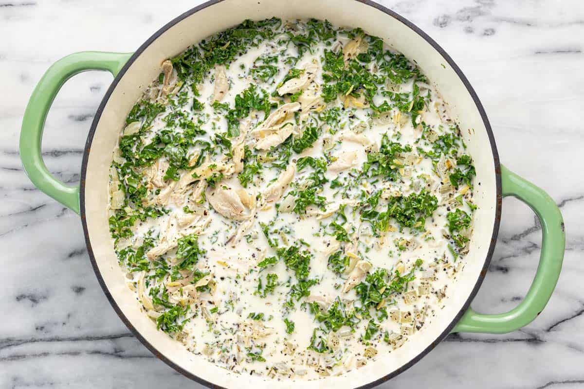 Large pan filled with ingredients to make lemon chicken orzo pasta. 