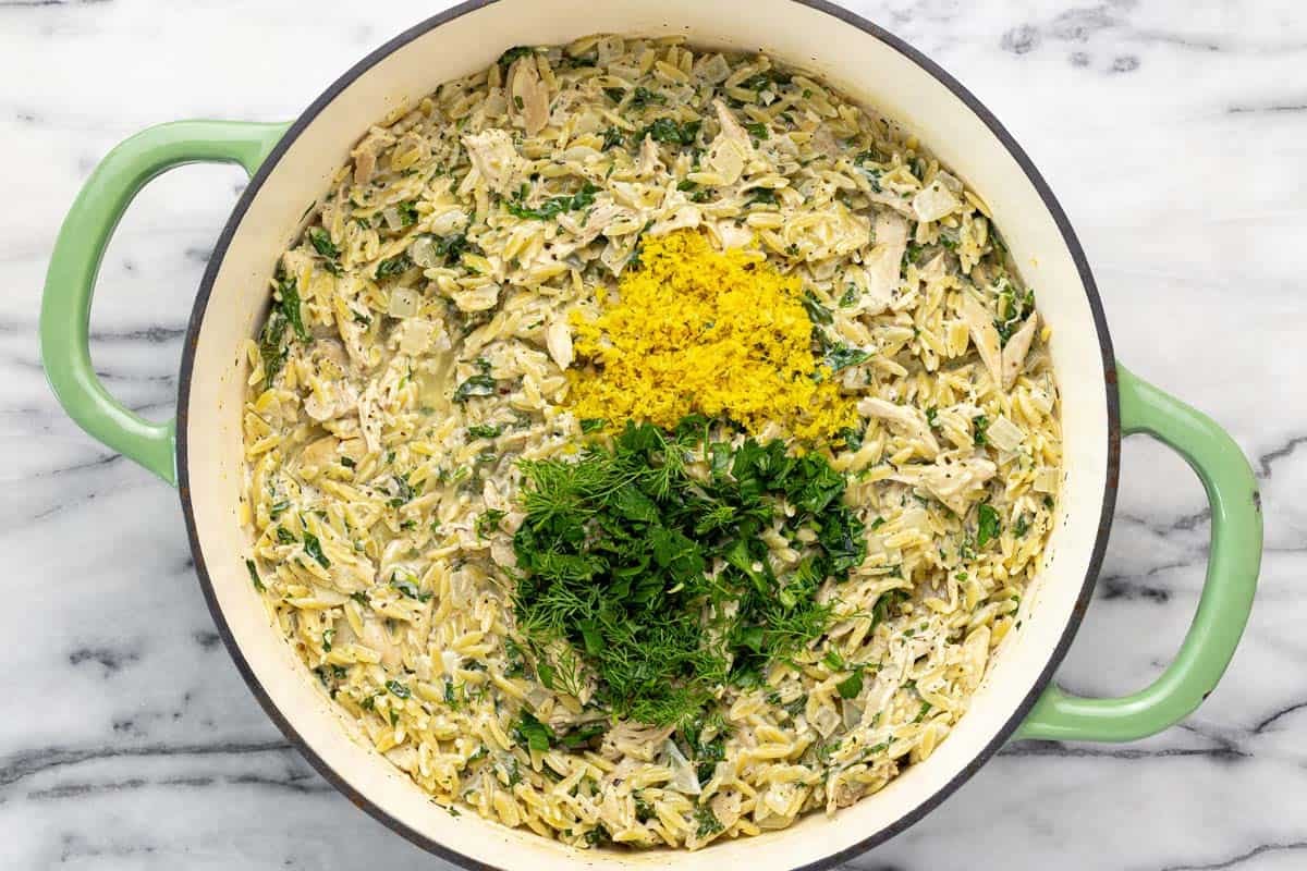 Lemon chicken pasta in a pan with lemon zest and fresh chopped herbs. 