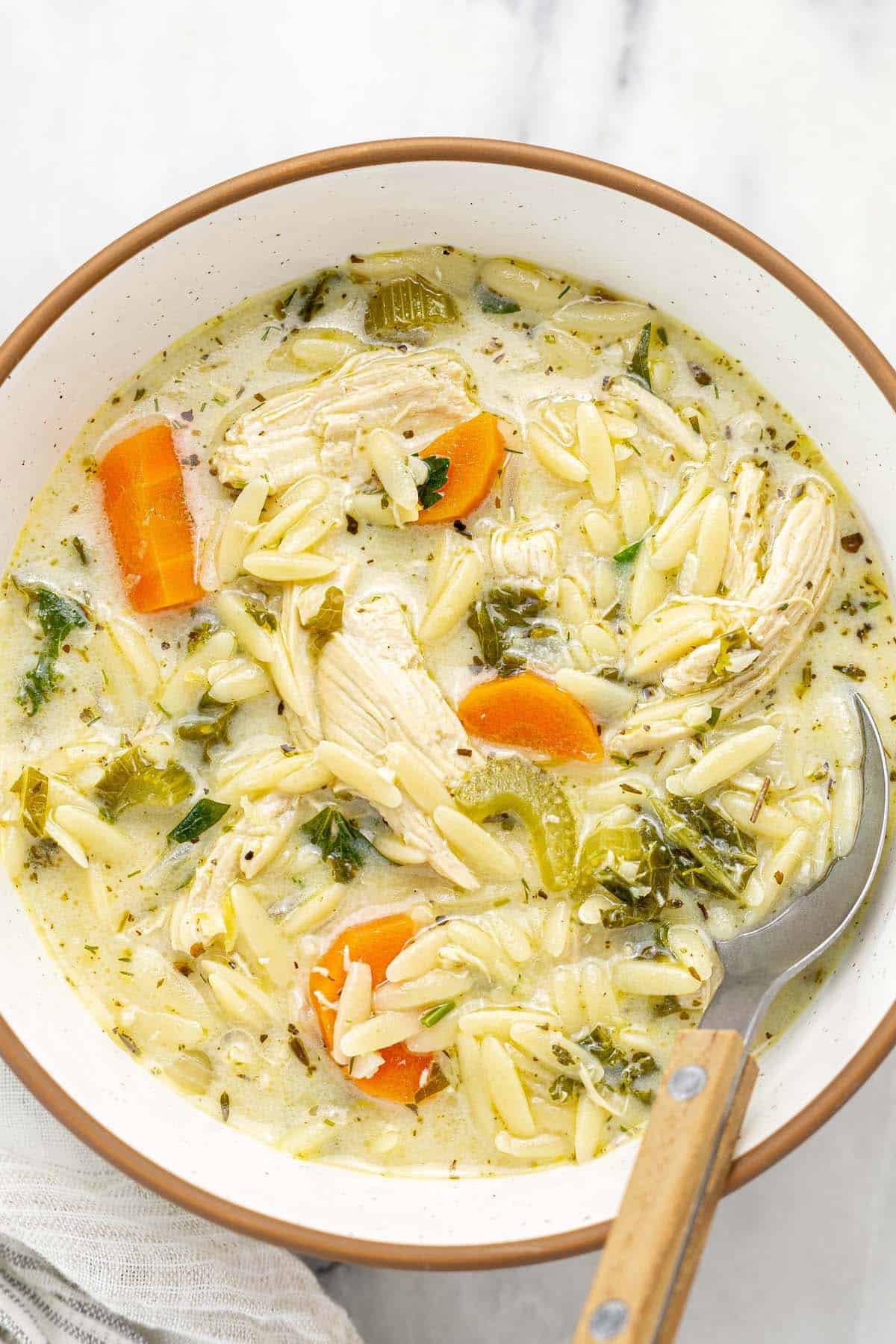 Bowl of lemon chicken orzo soup with a spoon.