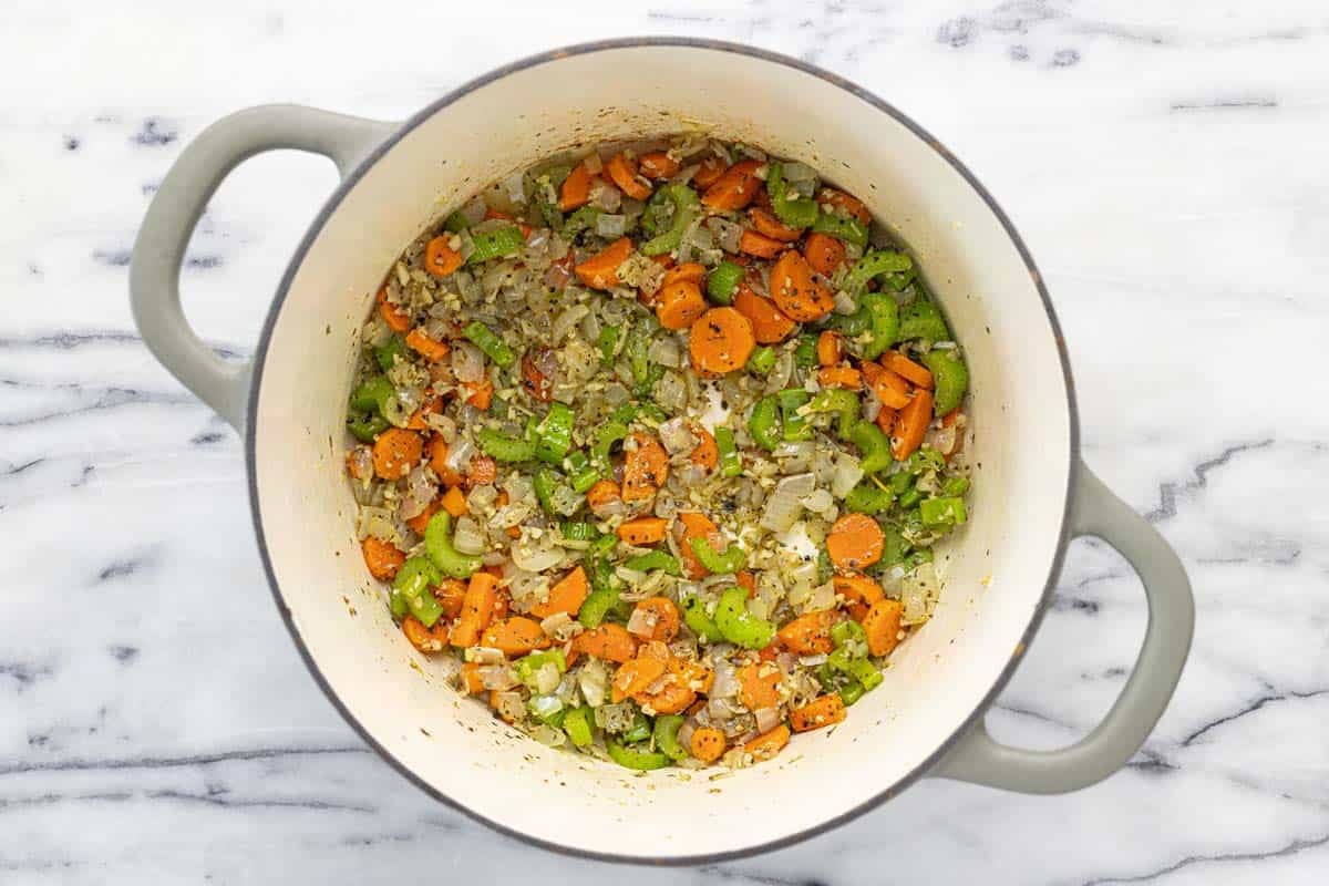 Large soup pot filled with sauteed veggies, garlic, and dried herbs. 