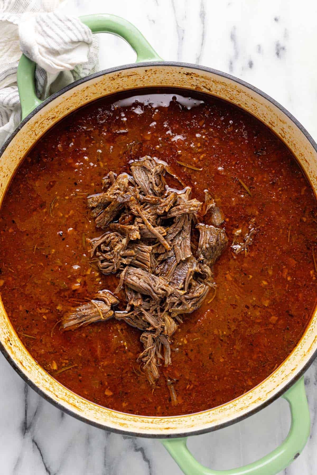 Shredded beef added back to a pan of sauce. 