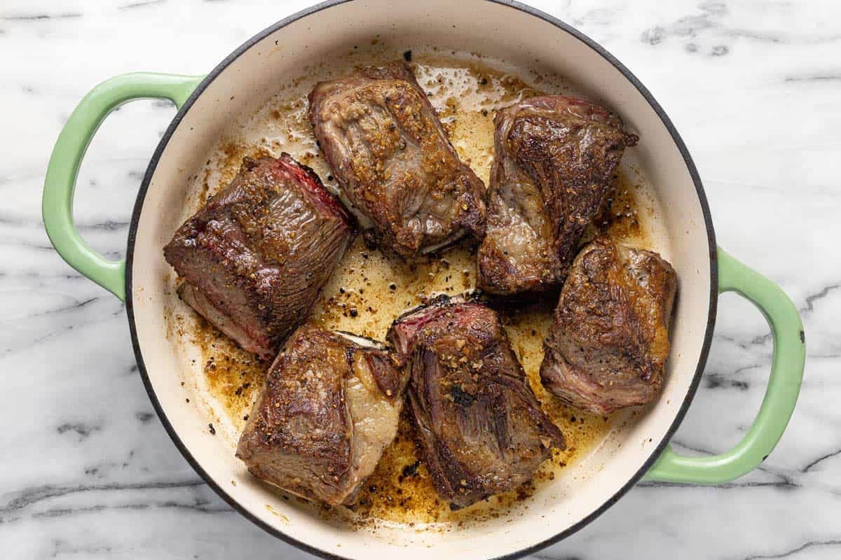 Large pan filled with seared short ribs. 