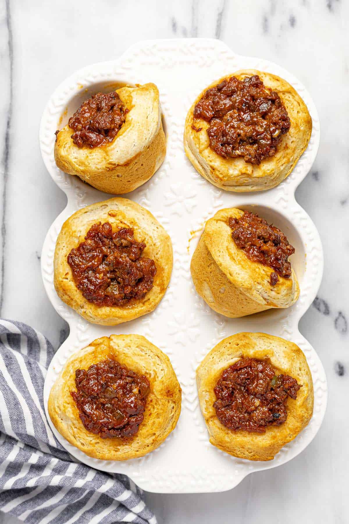 Muffin tin filled with fresh baked sloppy joe biscuits. 