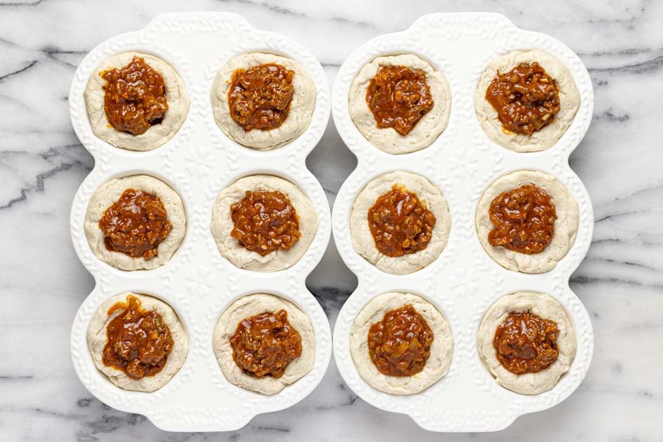 Two muffin tins with unbaked sloppy joe biscuits in them. 