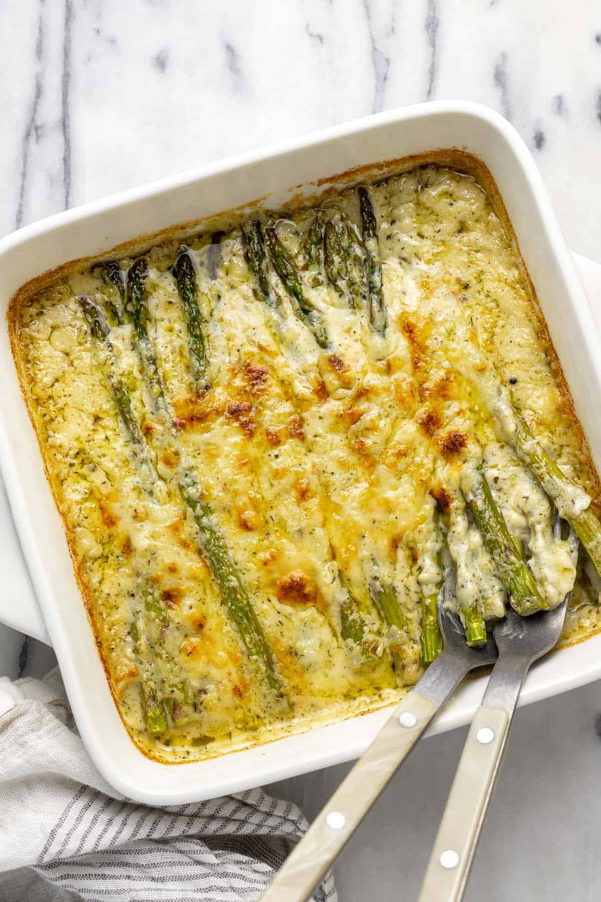 Freshly baked asparagus au gratin in a square baking dish.