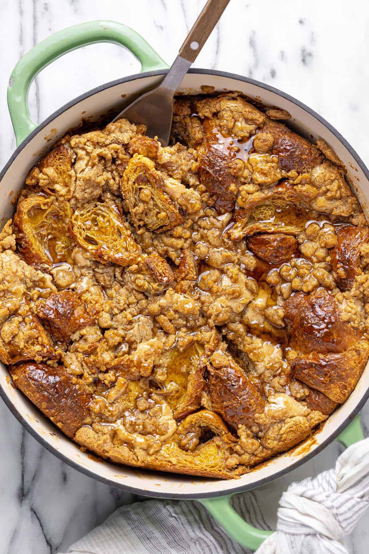 Large pan filled with croissant French toast bake topped with syrup.