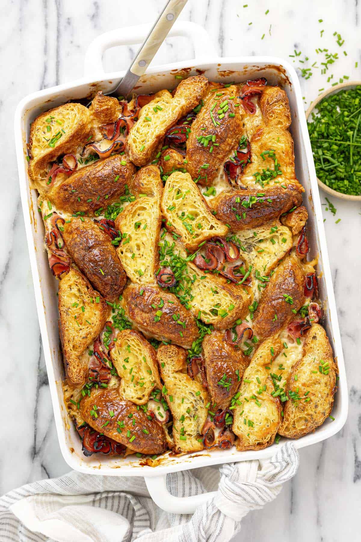 Baking dish filled with croissants, ham, and cheese in an egg custard bake.