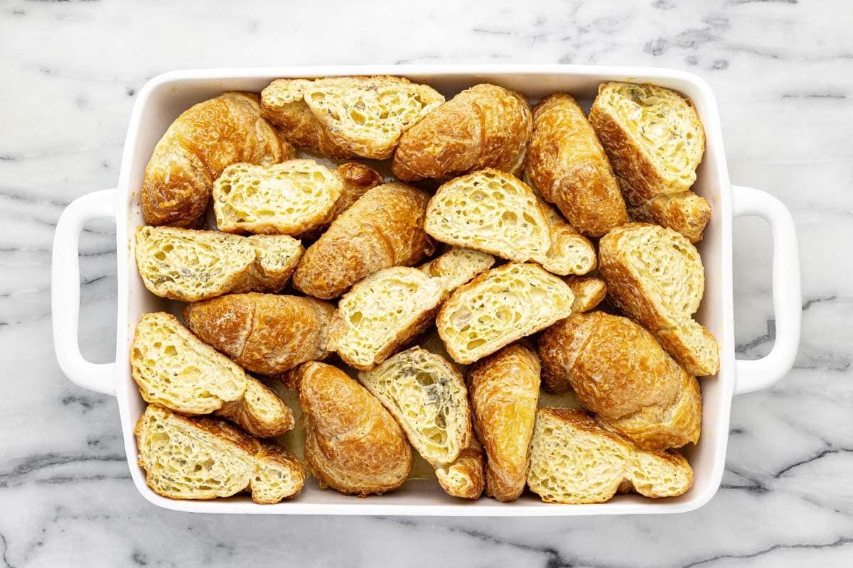Halved croissants soaked in egg custard in a large baking dish.