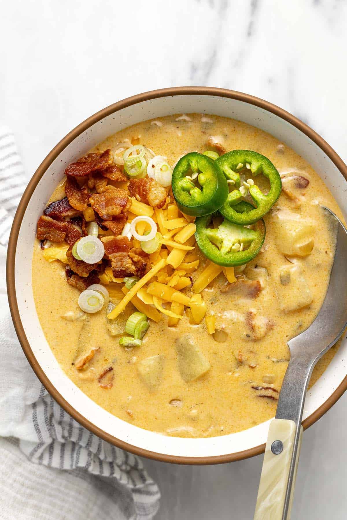 Bowl of jalapeno popper potato soup topped with cheese, bacon, and jalapenos. 