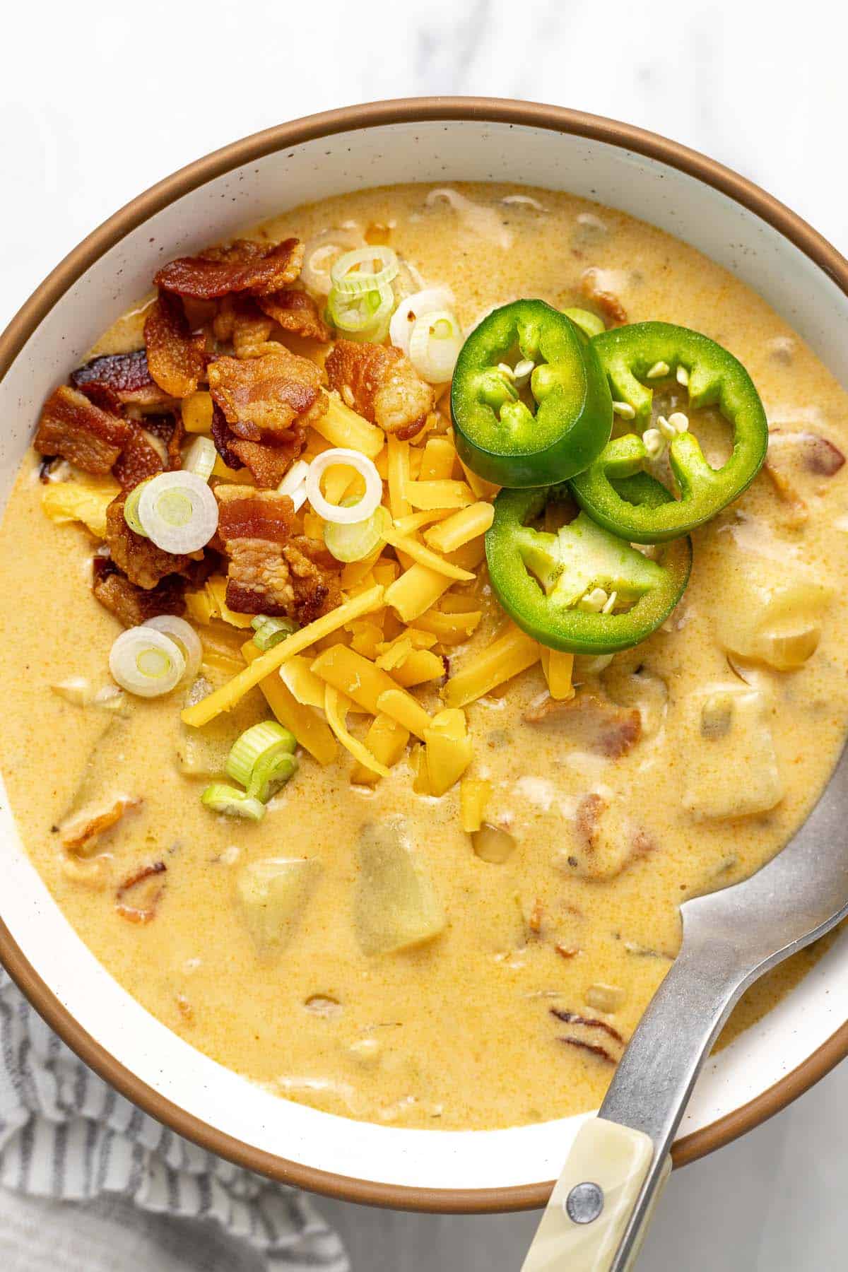 Bowl of jalapeno popper potato soup topped with cheese, bacon, and jalapenos. 