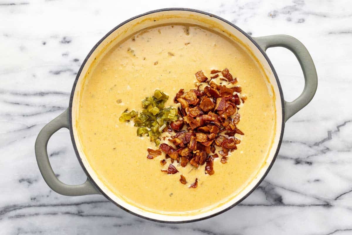 Bacon and diced jalapeno added to a pot of creamy soup. 