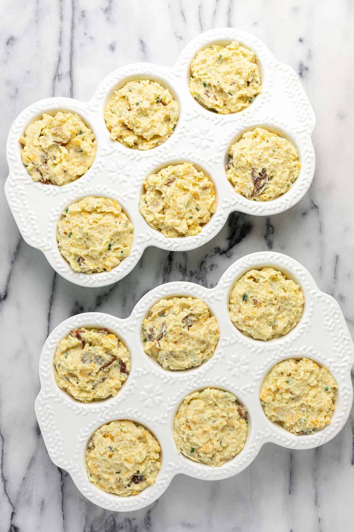 Mashed potato batter in two muffin pans. 