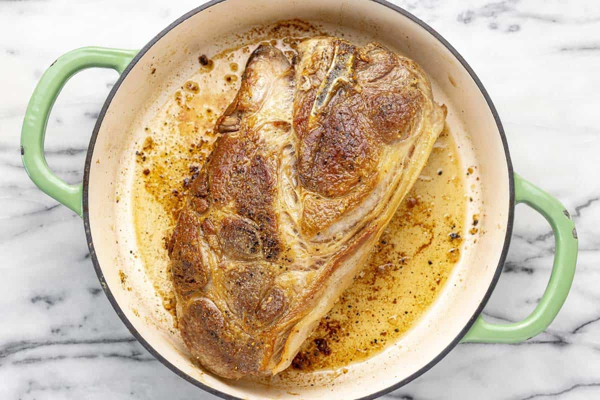 Seared pork shoulder in a large pan. 