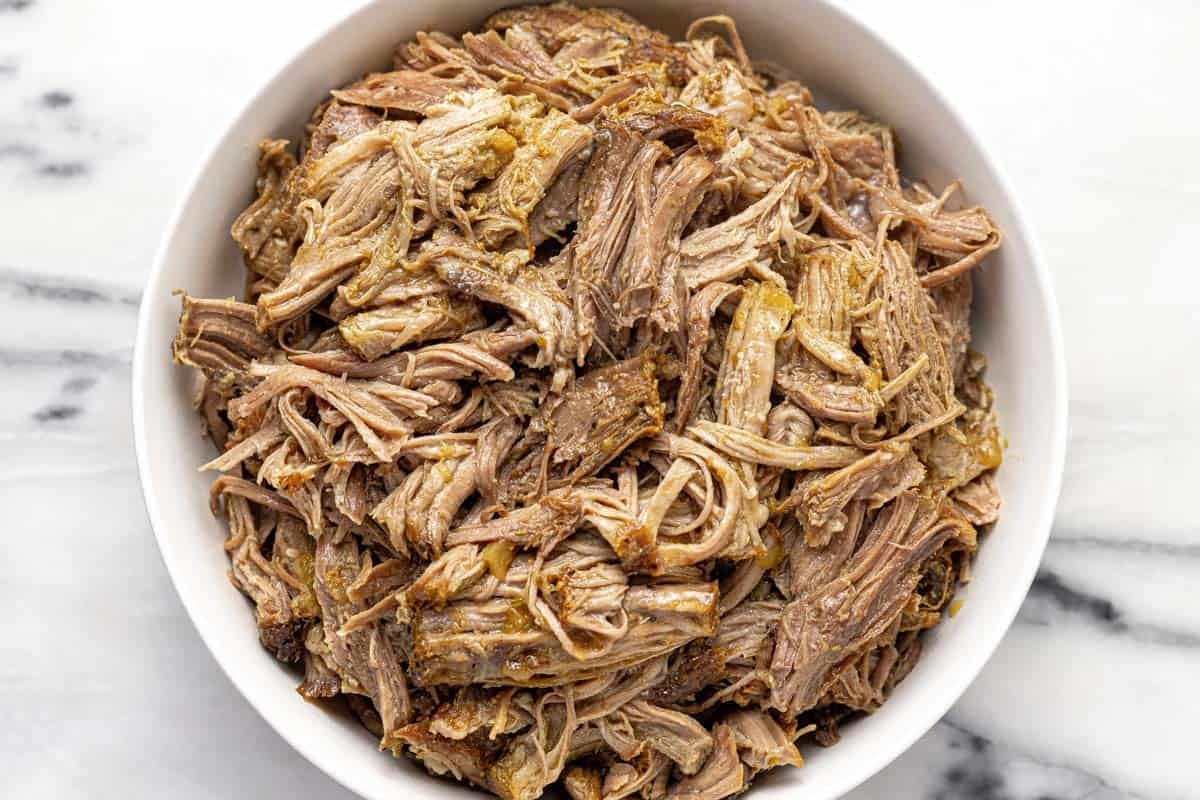 Shredded apple cider pork in a large bowl. 
