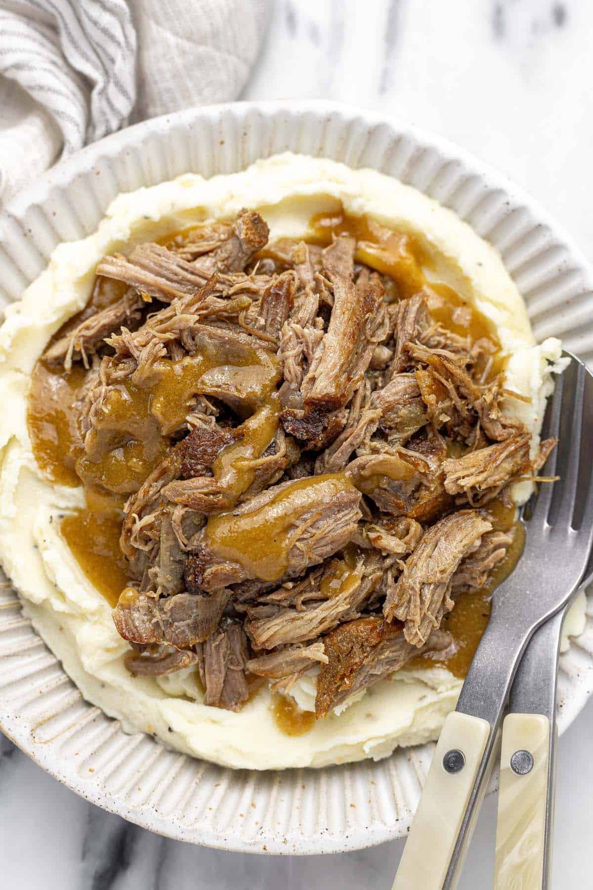 Bowl filled with mashed potatoes, shredded pork, and gravy. 