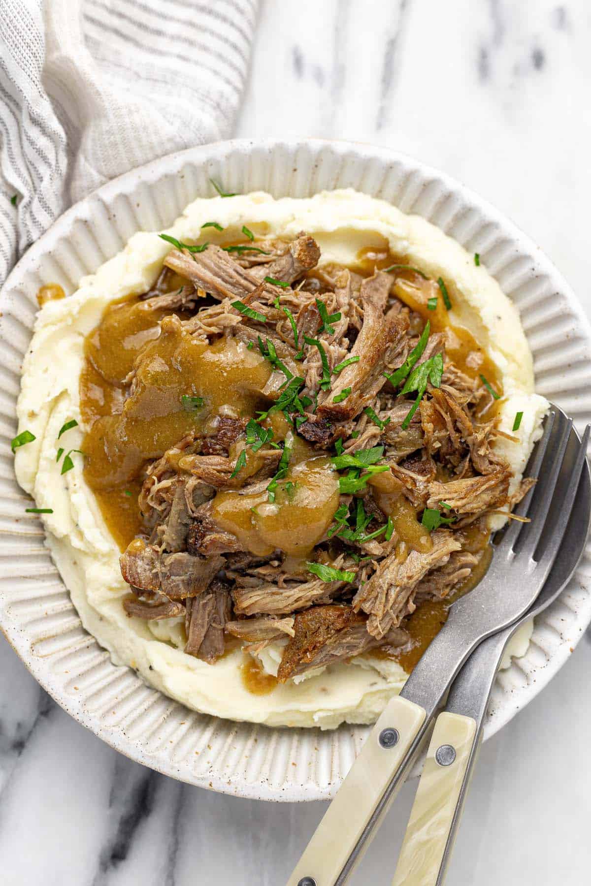 Bowl filled with mashed potatoes, shredded pork, and gravy. 