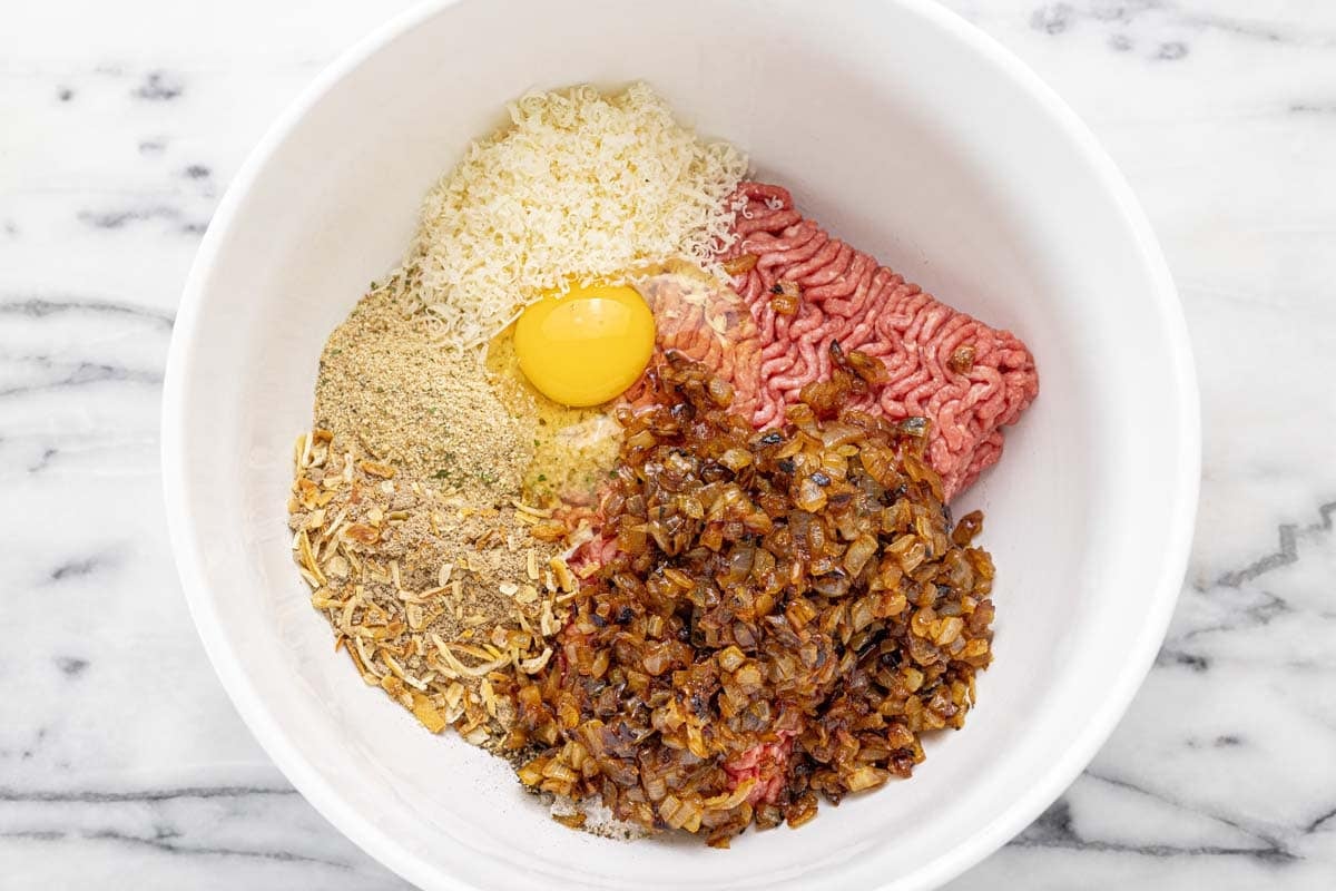 Bowl with ground beef, cheese, egg, caramelized onion, and breadcrumbs.