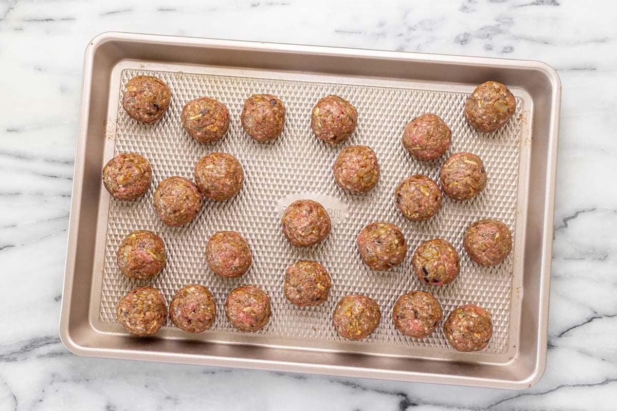 Raw meatballs on a baking sheet.