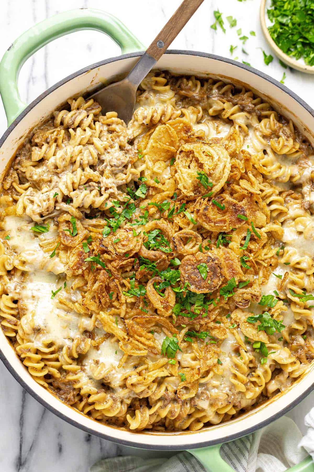 Large pan filled with creamy French onion pasta topped with cheese and parsley.