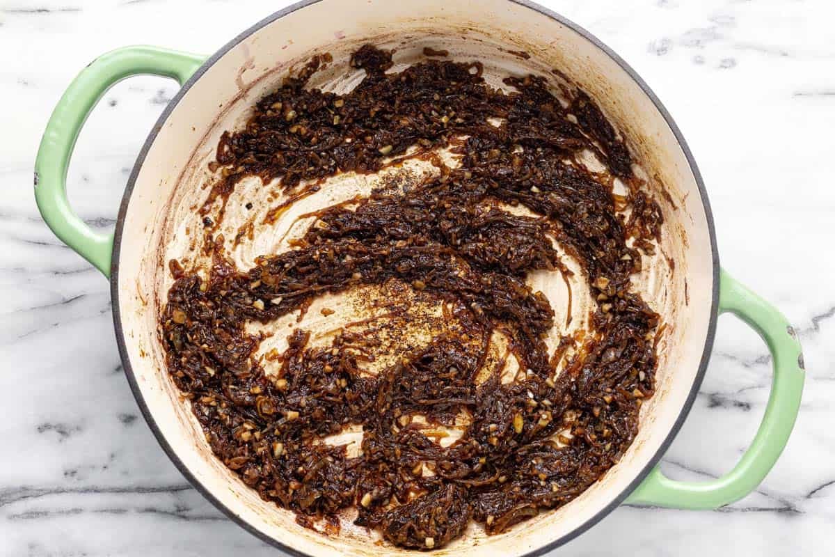 Caramelized onions in red wine in a large pan.