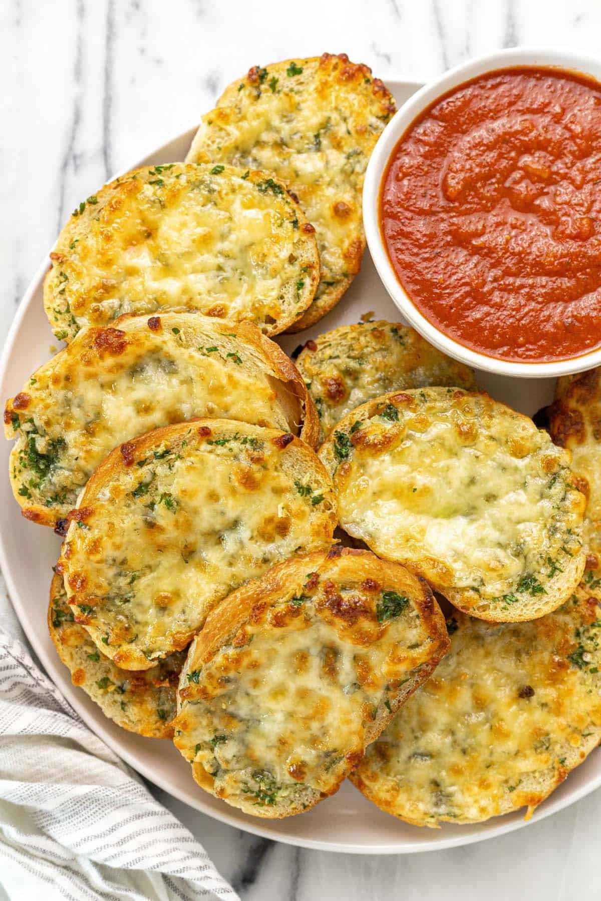 Plate of sliced garlic cheese bread with a bowl of marinara sauce.