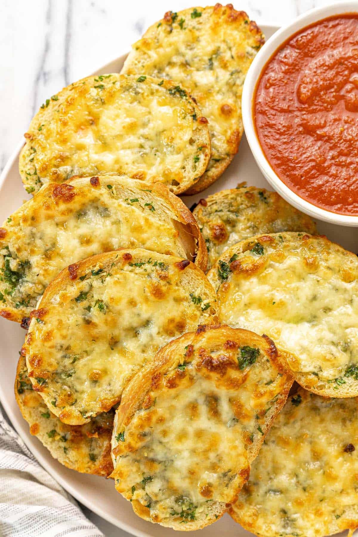 Plate of sliced garlic cheese bread with a bowl of marinara sauce.