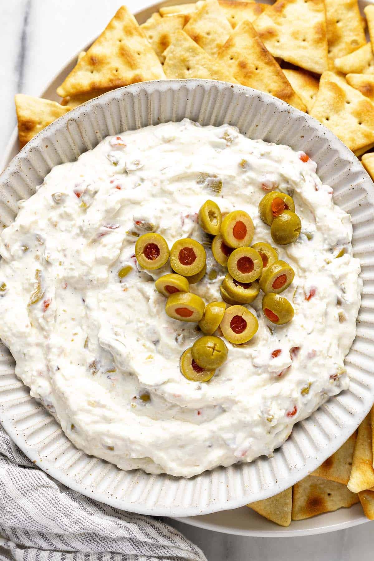 Bowl of olive dip on a plate of pita chips. 