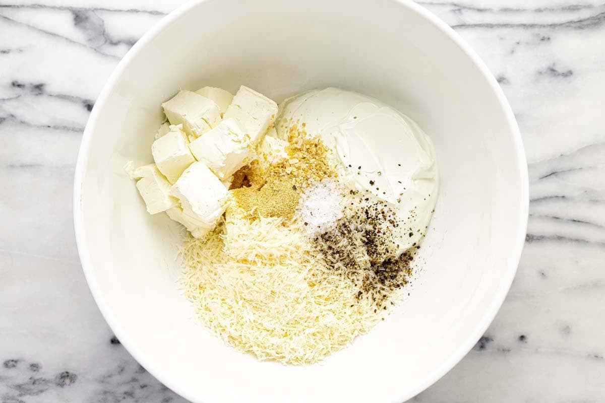 Bowl filled with ingredients to make creamy olive dip. 