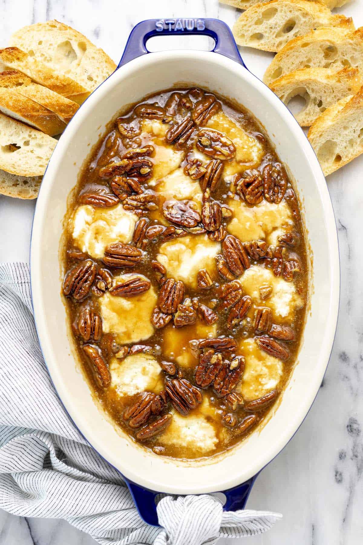 Baking dish filled with goat cheese and pecan pie topping.