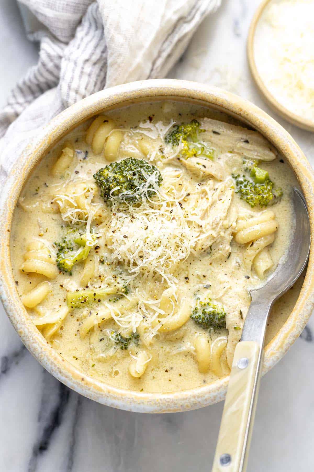 Bowl of chicken alfredo soup garnished with fresh Parmesan.