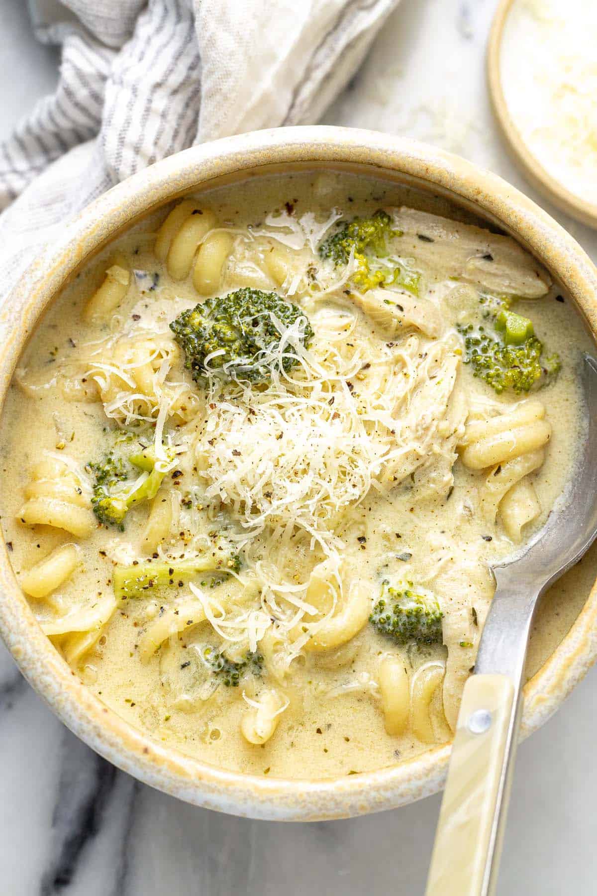 Bowl of creamy chicken alfredo soup garnished with Parmesan cheese.