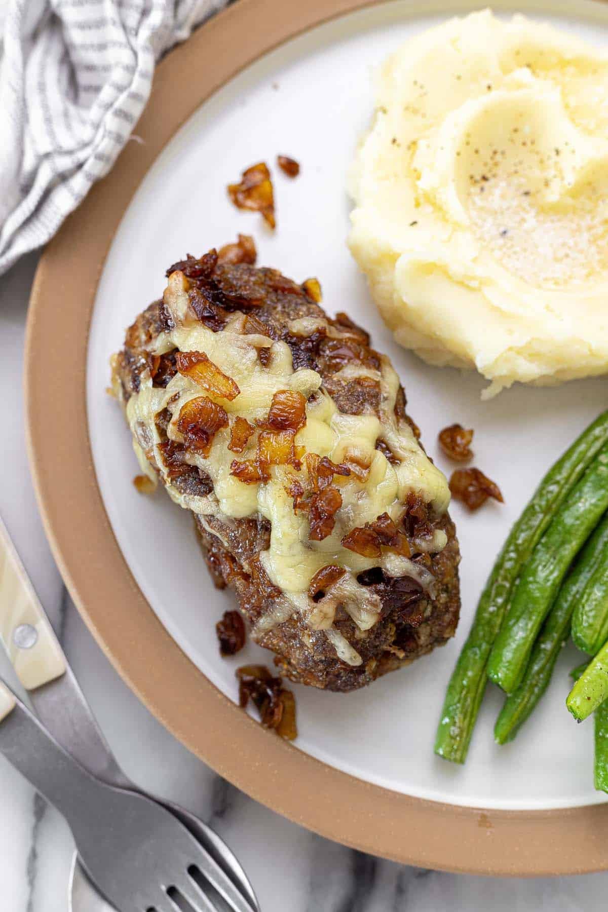 Plate filled with mini French onion meatloaf, mashed potatoes, and green beans.