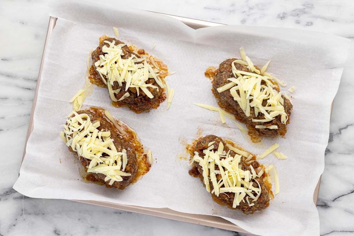 Caramelized onions and shredded cheese on top of mini French onion meatloaves.