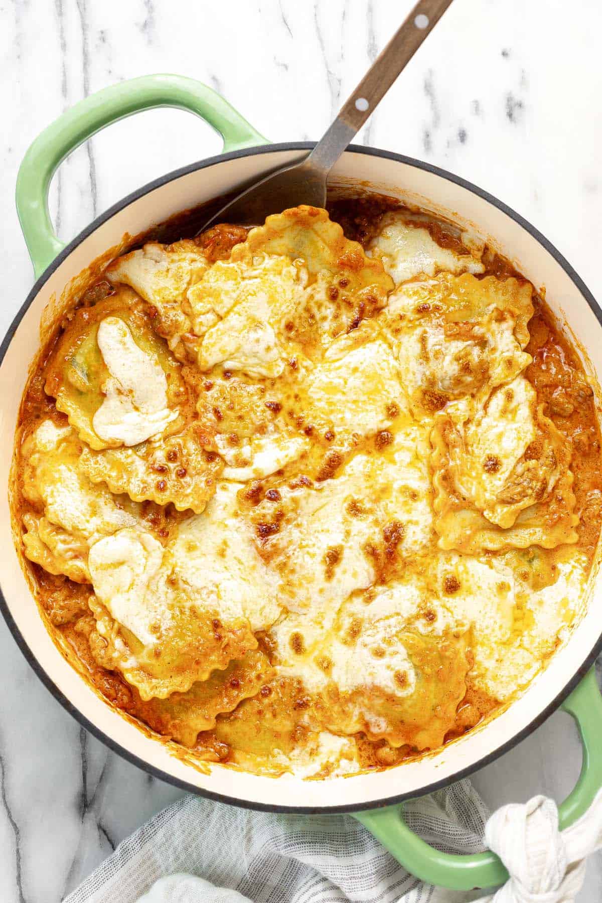 Large pan filled with creamy sausage ravioli topped with melty cheese.