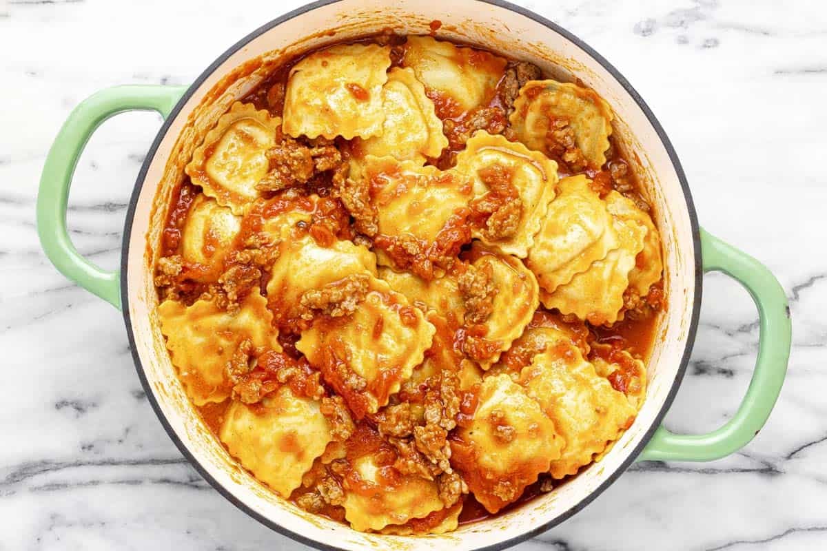Large pan filled with cheese ravioli in sausage sauce.