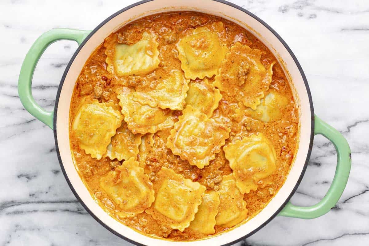 Creamy sausage ravioli in a large pan.