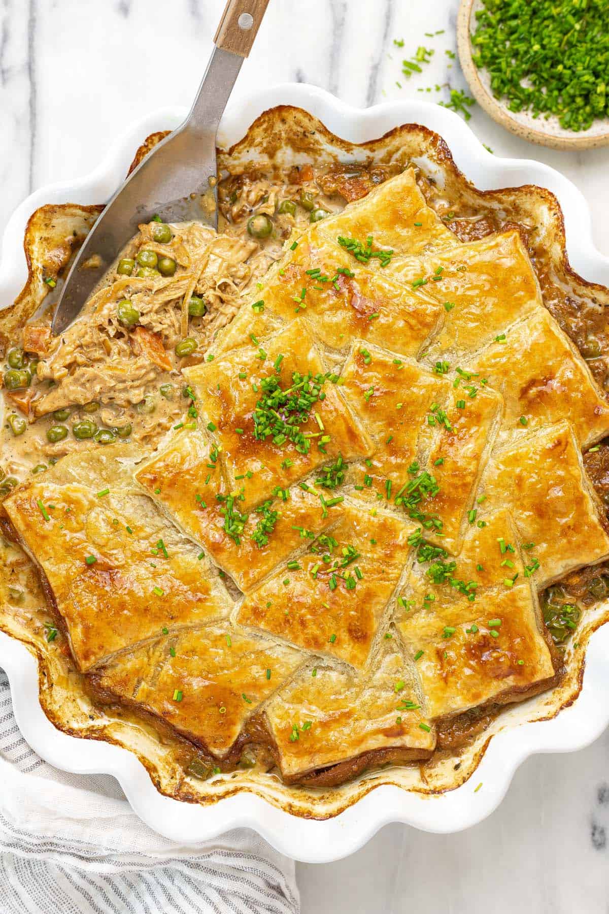 French onion chicken pot pie with golden puff pastry garnished with chives.