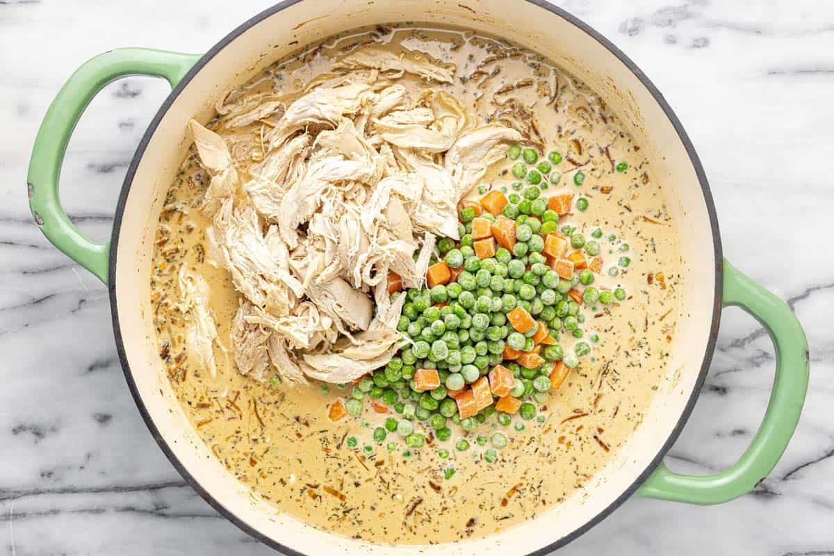 Shredded chicken and frozen veggies added to a pan of creamy onion sauce.