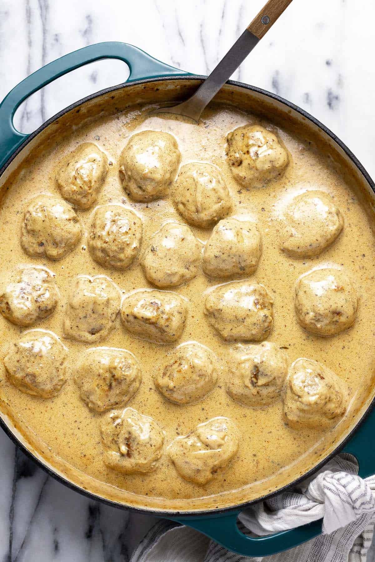 Creamy Swedish meatballs in a large pan with a spoon.
