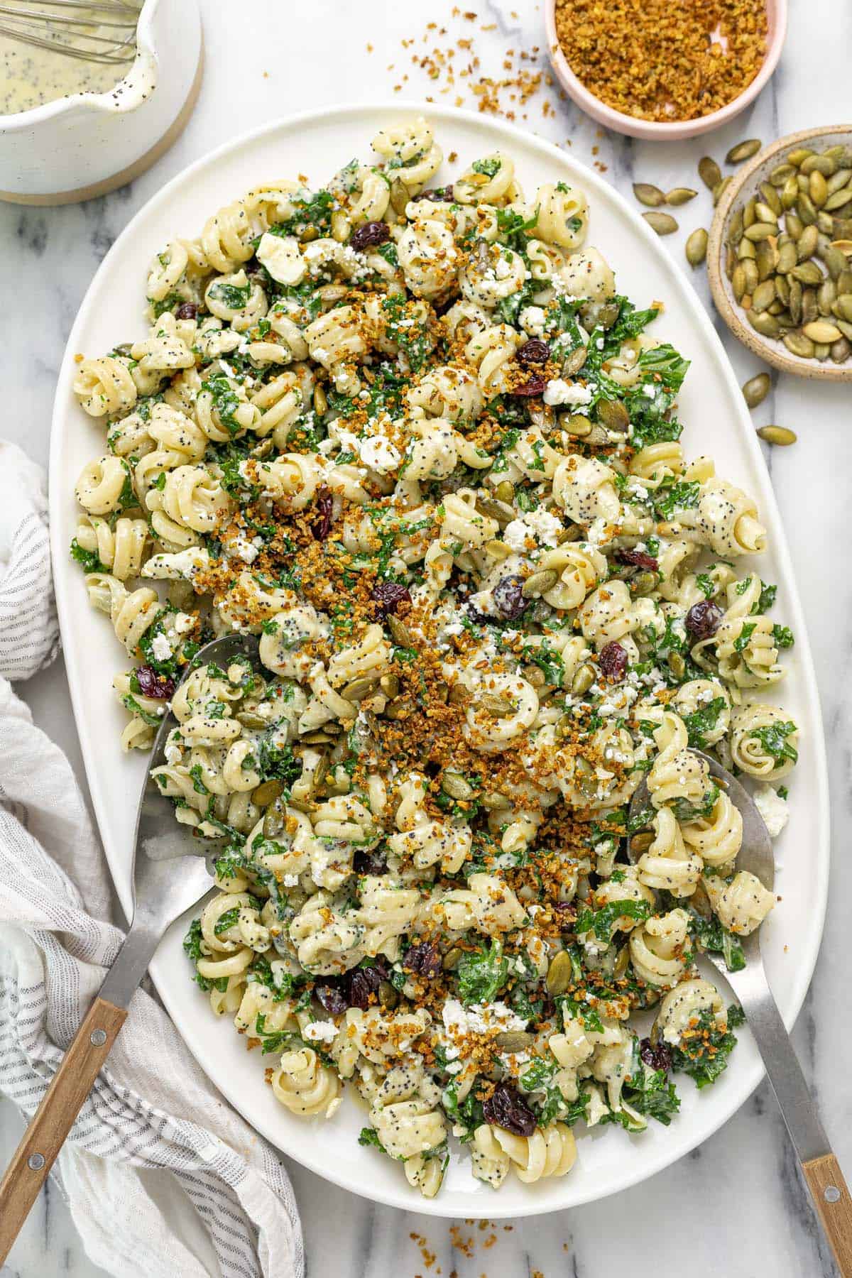Large platter with a winter pasta salad with kale, cherries, and pumpkin seeds.