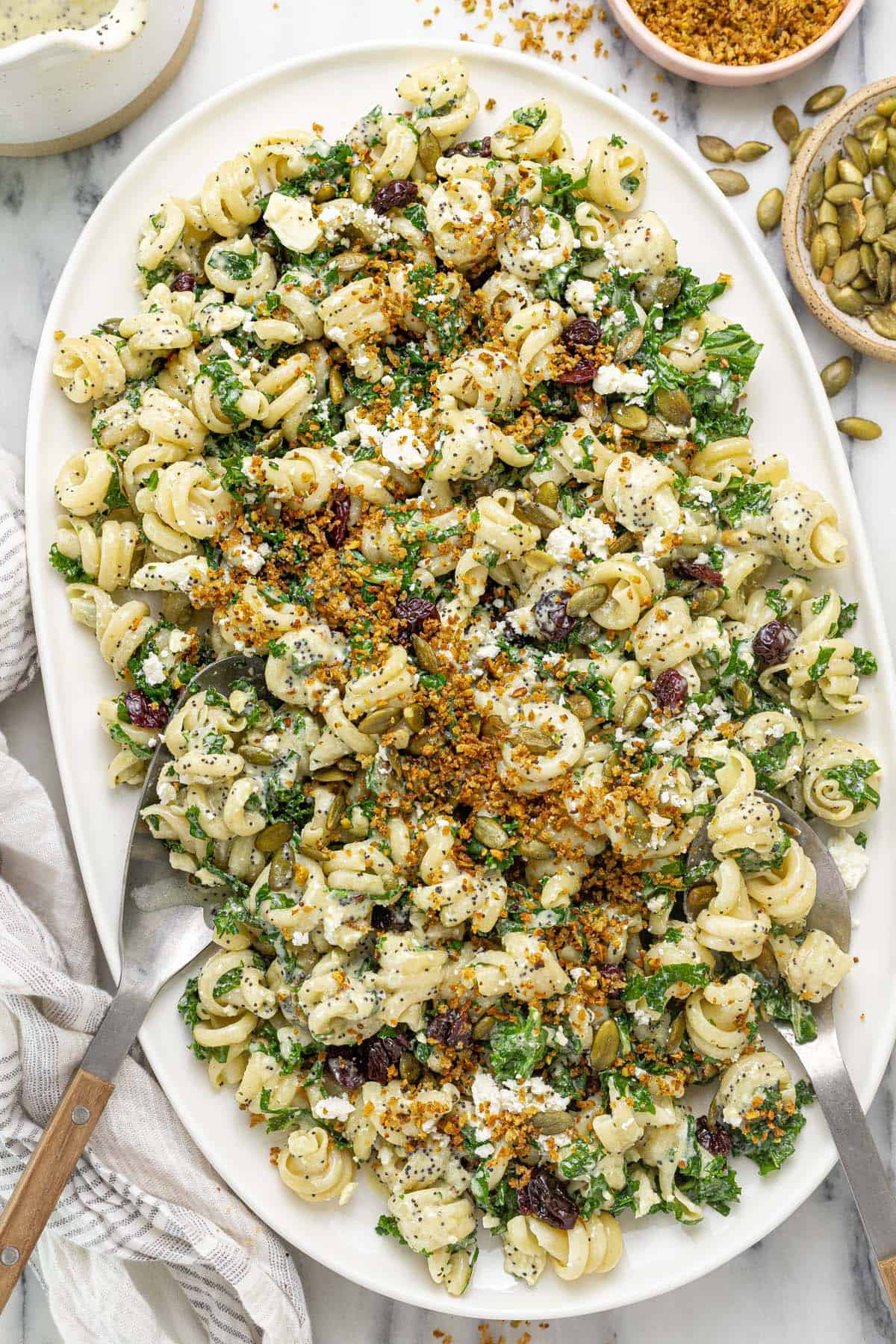 Large platter with a winter pasta salad with kale, cherries, and pumpkin seeds.