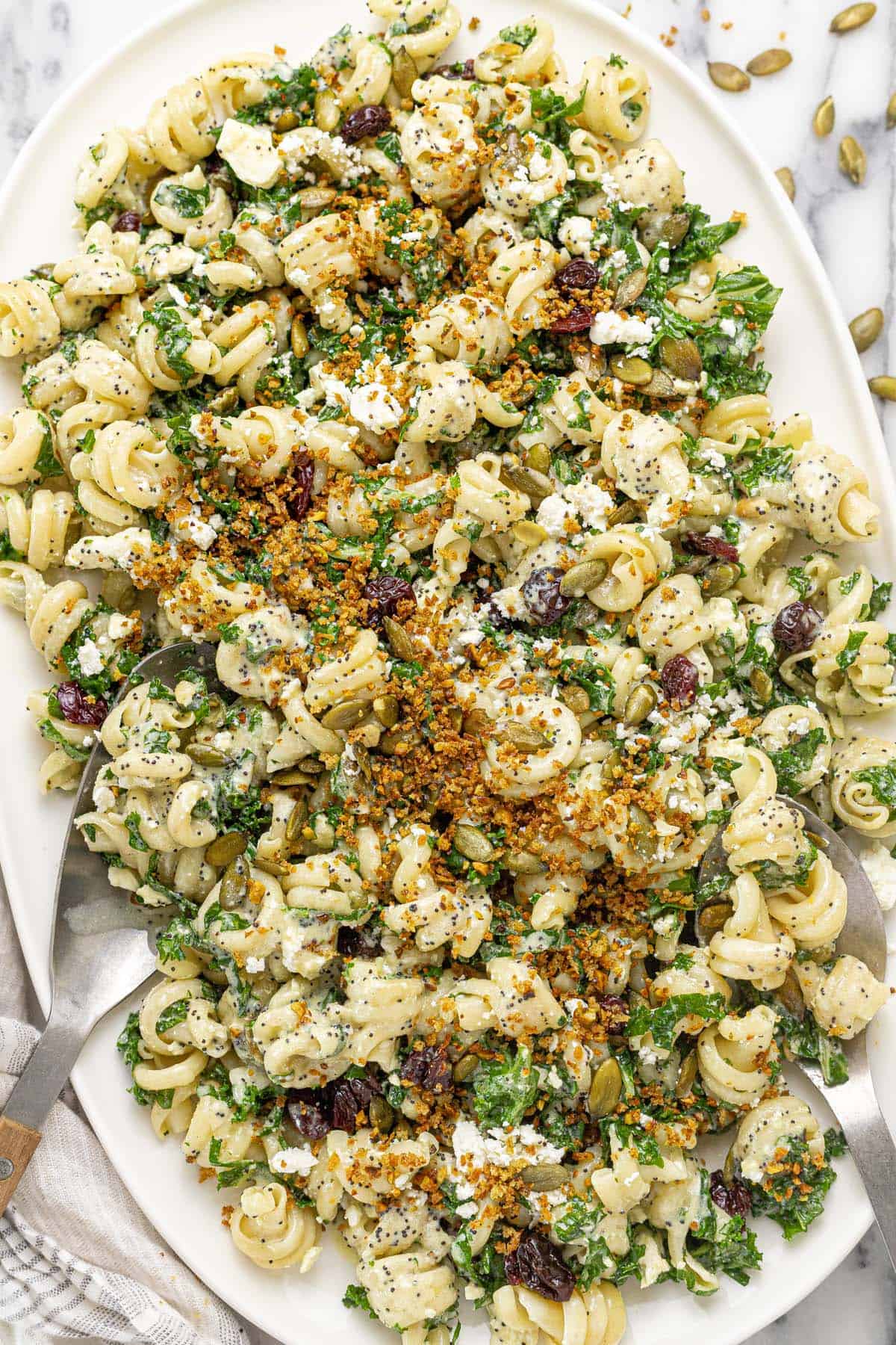 Large platter with a winter pasta salad with kale, cherries, and pumpkin seeds.
