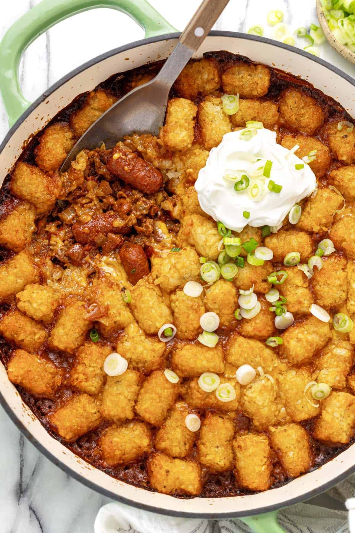 Large pan of chili cheese dog tater tot hot dish topped with sour cream.