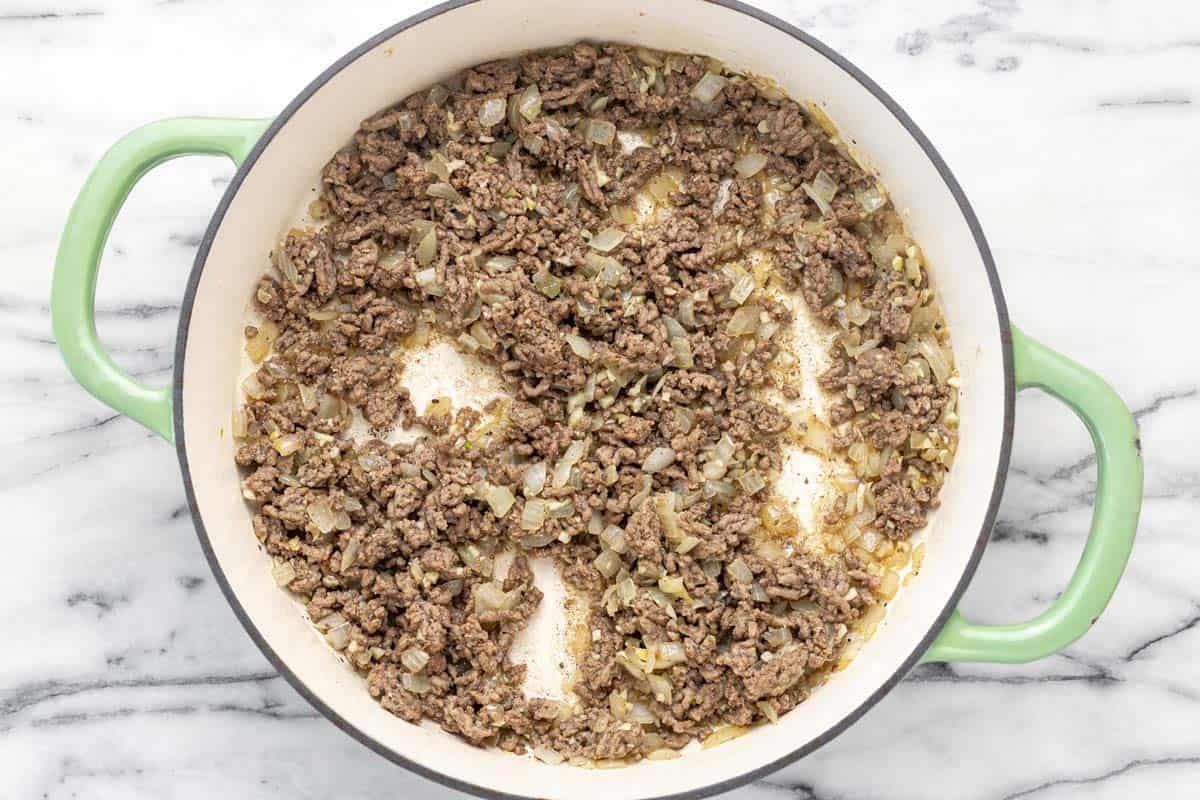Browned ground beef and sauteed onion in a large pan.