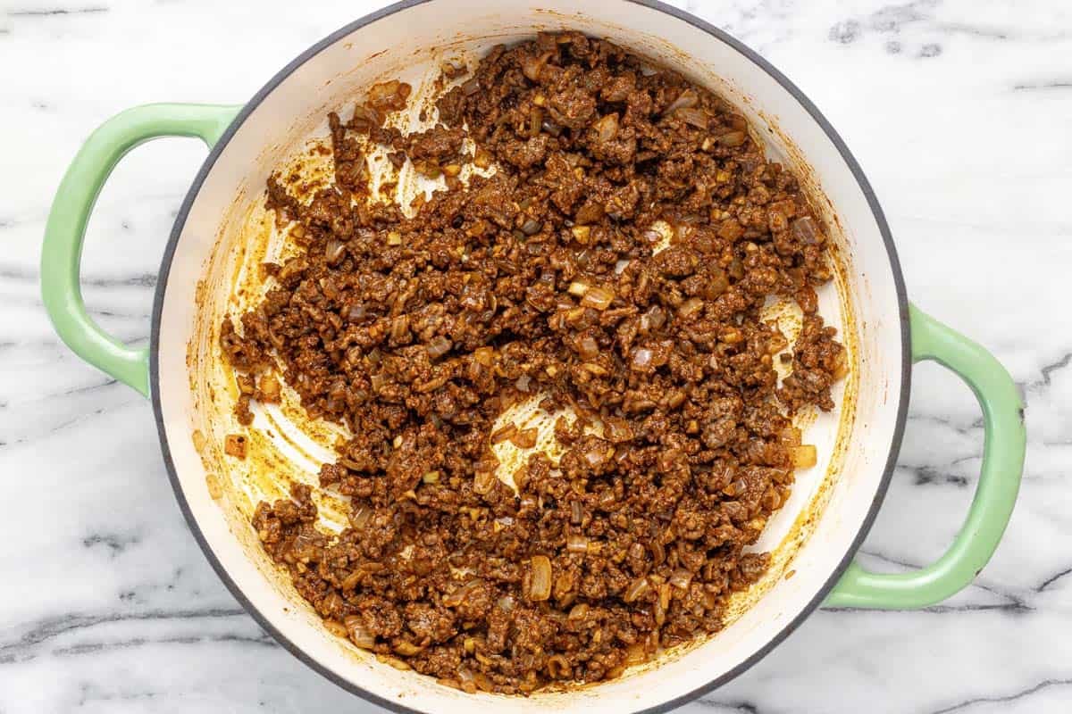 Large pan filled with tomato and spice seasoned ground beef.